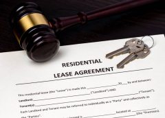 A residential lease agreement contract on a table with a gavel and keys laying on the document.