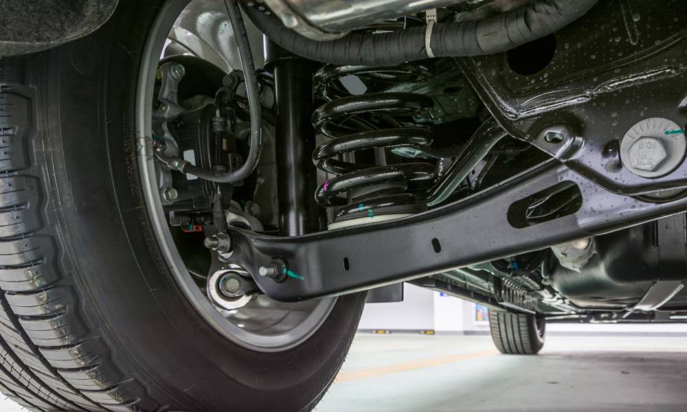 A close up view of a truck's undercarriage focuses on the interior side of the tire and a giant black spring.